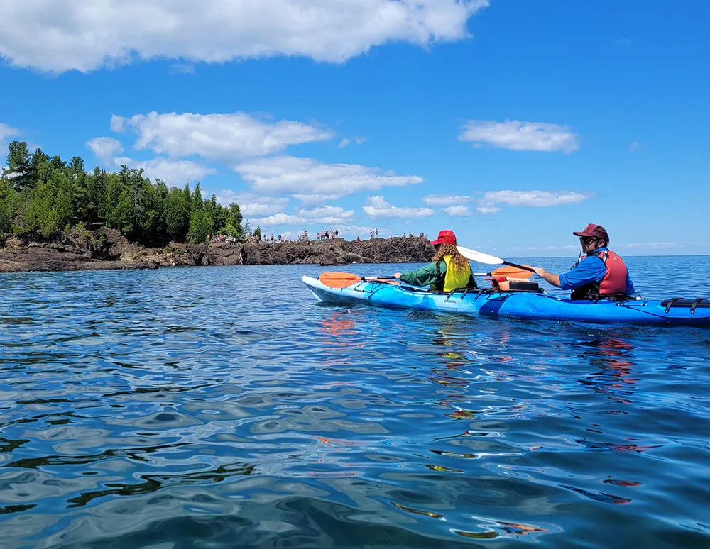 Presque Isla Black Rocks 05 (1) Kayakers paddling past a scenic rocky shoreline and sandstone cliffs near Presque Isle under a blue sky